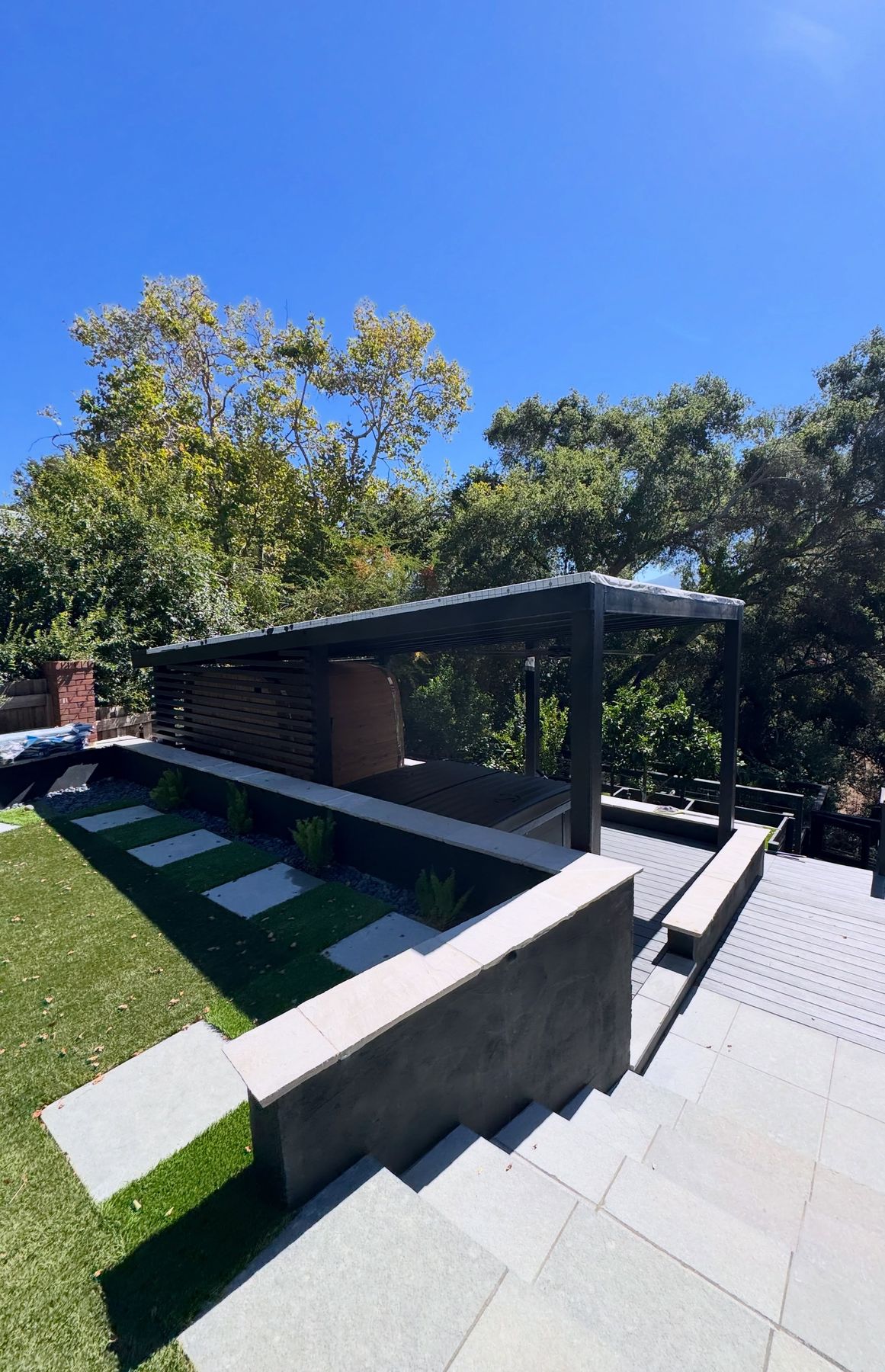 Finished backyard with a steel pergola, decking, turf and concrete steps